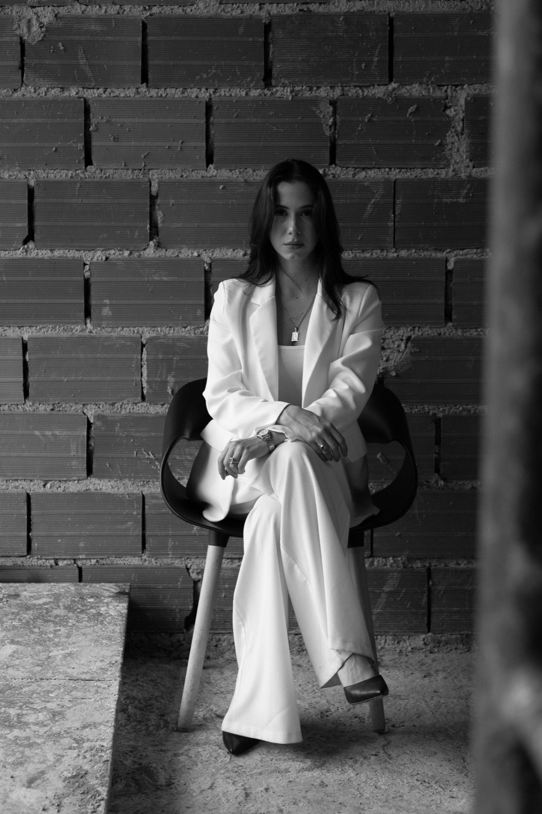 Andrea Domínguez, arquitecta, retrato editorial en blanco y negro sobre fondo de ladrillo en obra.